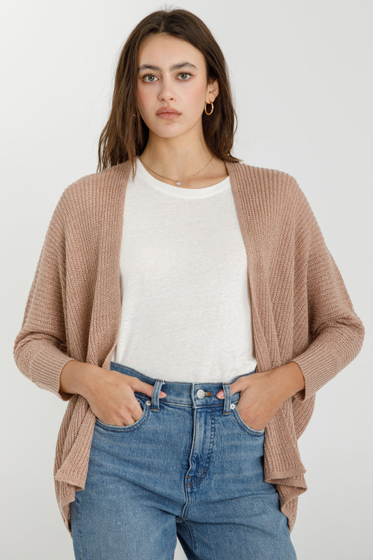 Woman wearing a mocha brown open front cardigan, white shirt, and blue jeans